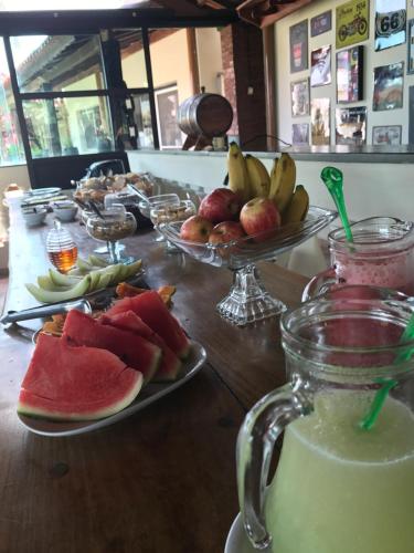 a table with plates of fruit and a glass of milk at Fazenda Mantiqueira e Restaurante in Camanducaia