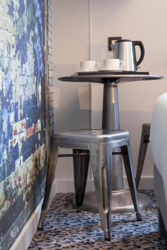 une table en métal avec deux tasses dessus sur un tapis dans l'établissement Georgette Hôtel & Restaurant, à Paris