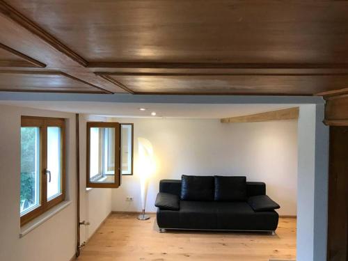 a living room with a black couch in a room at Echtes Schwarzwaldhaus - Traditionell & Modern in Bernau im Schwarzwald