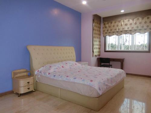 a bedroom with a bed with purple walls and a window at Shuang Yang Sekinchan Homestay 6 in Sekincan