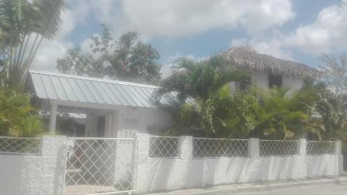 a white fence in front of a house with palm trees at Bayahibe Guest House Hotel in Bayahibe