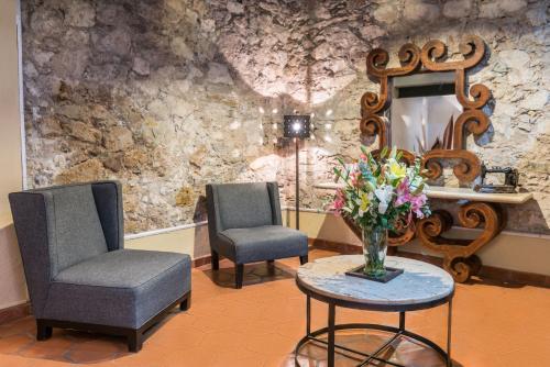 uma sala de espera com duas cadeiras e um vaso de flores sobre uma mesa em Hotel Casa Virreyes em Guanajuato