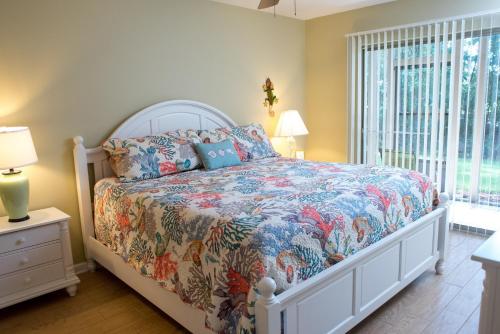 a bedroom with a bed with a floral bedspread at Pawleys Island Vacation Rentals llc in True Blue
