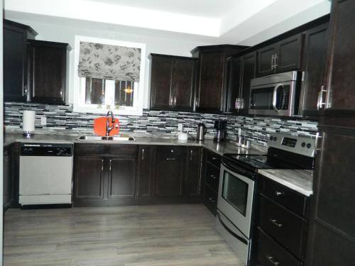 a kitchen with dark wooden cabinets and white appliances at Whitsha Inn B&B in Twillingate
