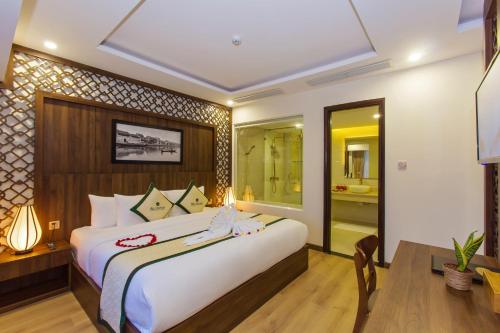 a bedroom with a large bed and a table and a desk at Ally Beach Boutique Hotel Hoian in Hoi An