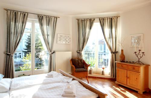 ein Schlafzimmer mit einem großen Bett und großen Fenstern in der Unterkunft Villa Saxonia by Rujana in Binz