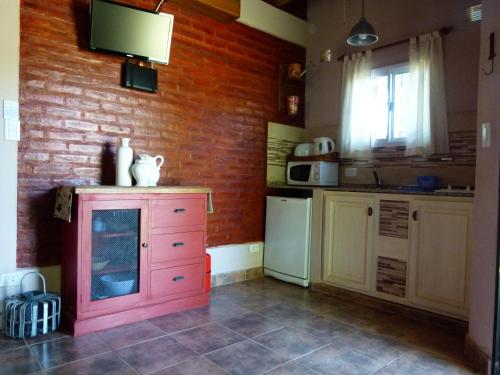 a kitchen with a pink dresser and a brick wall at Guidai Bilu in San José