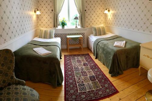 Habitación con 2 camas, silla y ventana en 27ans Nattlogi, en Vadstena