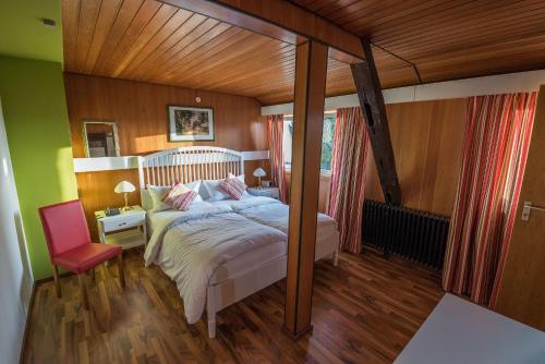 a bedroom with a bed and a red chair at Landgasthof & Hotel "Zum Schwan" GmbH in Trippstadt