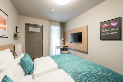 a bedroom with a bed and a flat screen tv at stattHotel Weimar in Weimar