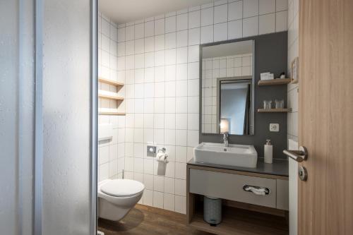 a bathroom with a toilet and a sink and a mirror at stattHotel Weimar in Weimar