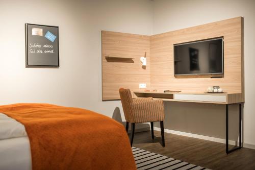 a bedroom with a desk with a tv and a bed at stattHotel Weimar in Weimar