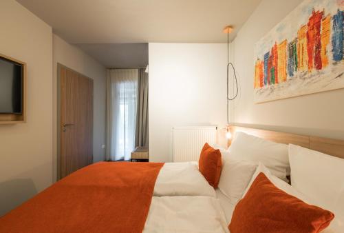 a bedroom with a large bed with white sheets and orange pillows at stattHotel Weimar in Weimar