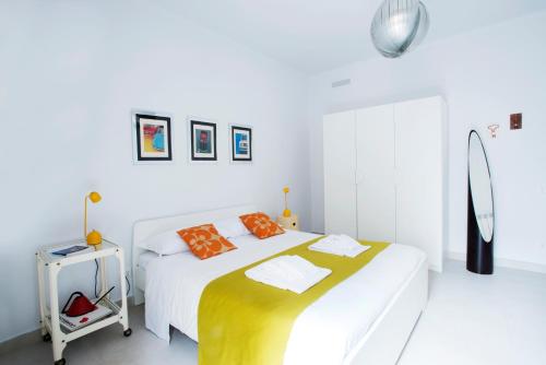 una camera bianca con un grande letto con cuscini arancioni di Interno16HolidayHome a Napoli
