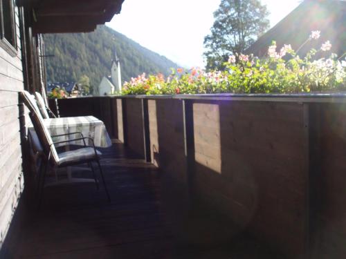 a balcony with a chair and flowers on a house at Appartementhaus zur Loipe in Sankt Jakob in Defereggen