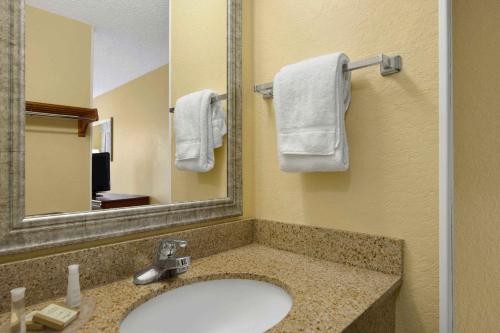 a bathroom with a sink and a mirror and towels at Baymont By Wyndham Gainesville I-75 in Gainesville