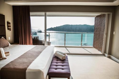 a bedroom with a large window with a view of the water at Caixa D'aço Exclusive Hotel in Porto Belo
