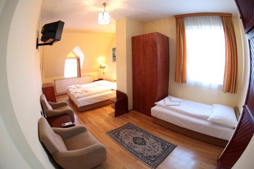 Habitación pequeña con 2 camas y 2 sillas en Hotel Bara Junior en Budapest