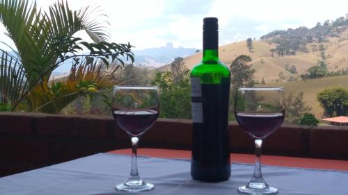 a bottle of wine and two glasses on a table at Pousada Refugio Sol e Brisa in São Bento do Sapucaí