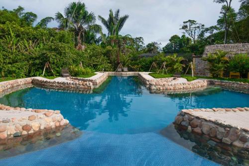 una piscina en un complejo con una pared de roca en Hakuna Matata Amazon Lodge en Archidona