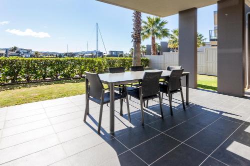 a dining table and chairs on a patio at Sovereign Pier On The Waterways in Whitianga
