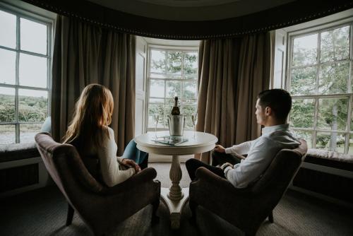 a man and woman sitting around a table with a bottle of wine at Banchory Lodge Hotel in Banchory