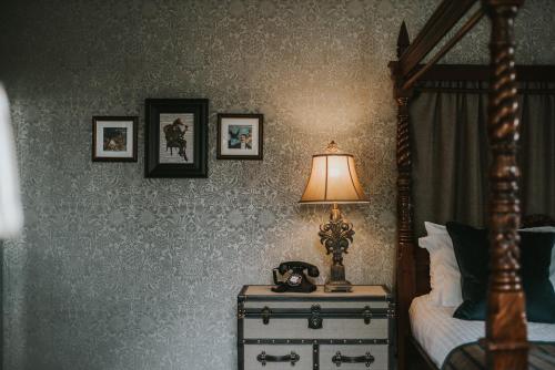 a bedroom with a bed and a lamp on a dresser at Banchory Lodge Hotel in Banchory