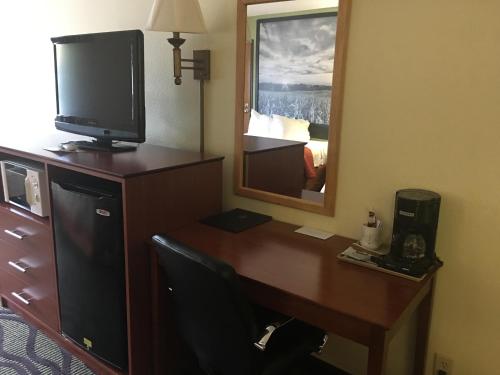 a room with a desk with a television and a mirror at Super 8 by Wyndham Newton in Newton