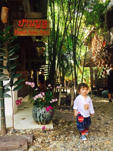 a little boy standing in front of a flower shop at BaanBooLoo Village in Chiang Mai