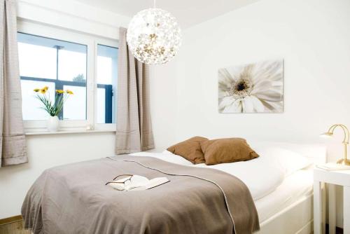 ein weißes Schlafzimmer mit einem Bett und einem Kronleuchter in der Unterkunft Villa Meeresrauschen Wohnung 14 in Pelzerhaken