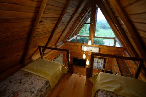 an attic room with two beds and a large window at Casa na Árvore in Santa Cruz do Sul