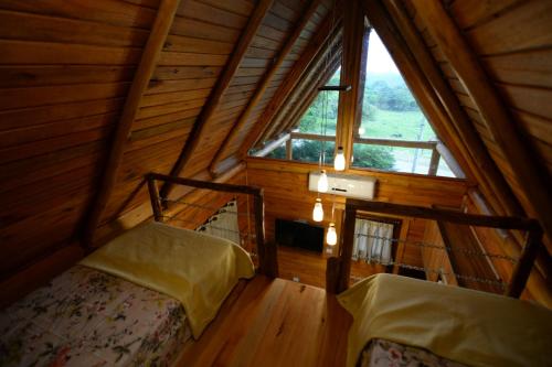 een zolderkamer met 2 bedden en een groot raam bij Casa na Árvore in Santa Cruz do Sul