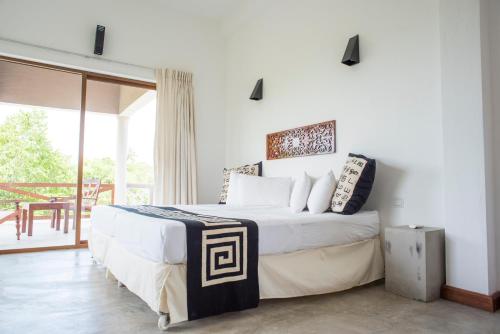a bedroom with a large bed and a balcony at Nagenahira Beach Villa in Nilaveli