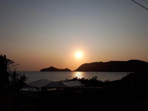 a sunset over a body of water with the sun setting at Kostas Apartments & studios in Agios Georgios Pagon