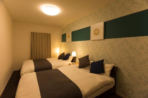 2 Betten in einem nebeneinander liegenden Hotelzimmer in der Unterkunft The Metropolitan in Fukuoka