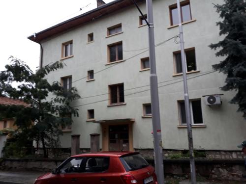 un coche rojo estacionado frente a un edificio en Apartment ILIEVI en Pleven