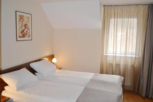 een slaapkamer met een bed met witte lakens en een raam bij Casa Retezat in Rîu de Mori