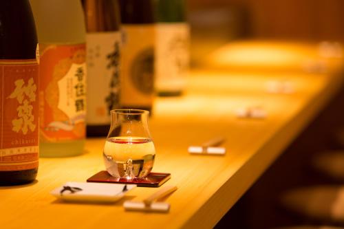 una copa de vino sentada en una mesa junto a una botella en Kinsui Annex, en Toyooka