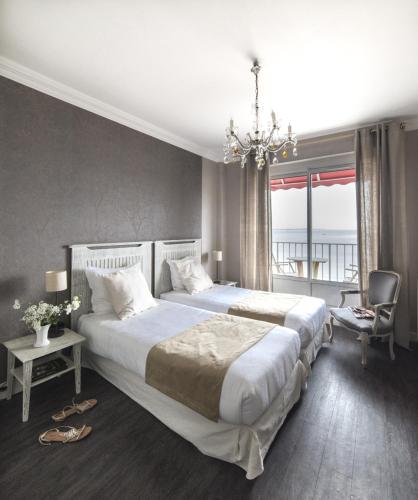 a large bedroom with two beds and a chandelier at Family Golf Hotel in Royan