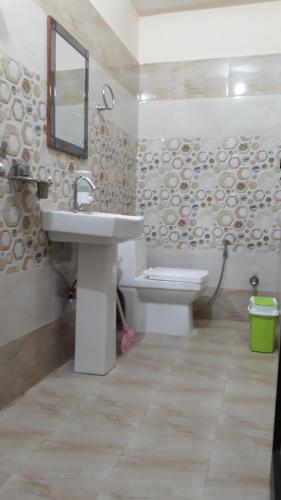 uma casa de banho com um lavatório, um WC e um espelho. em Hostel Cozy Beds em Rishikesh