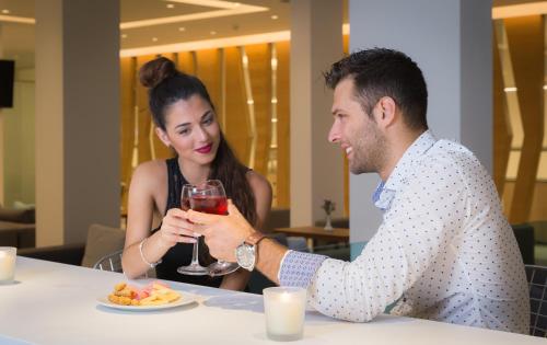 a man and woman sitting at a table with a glass of wine at Acharavi Beach Hotel in Acharavi