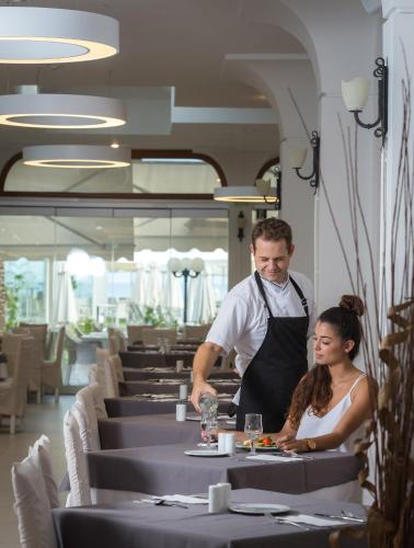 a man and a woman preparing food in a restaurant at Acharavi Beach Hotel in Acharavi