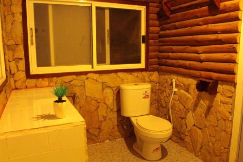 a bathroom with a toilet and a stone wall at Sangthain hills in Ko Samed