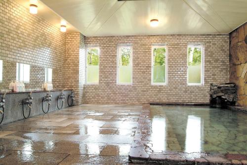 a swimming pool in a room with a brick wall at Hotel Kodama in Yamanouchi