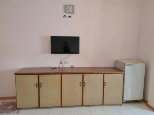 a television sitting on top of a counter next to a refrigerator at New Budget Inn Hotel in Cukai