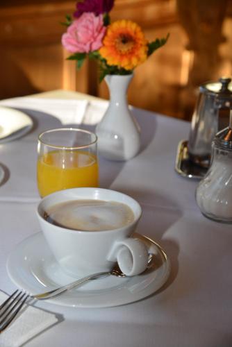 a cup of coffee on a table with a vase of flowers at Hotel Ostaria Posta in San Martino in Badia