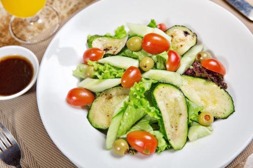 a white plate with a salad with tomatoes and vegetables at Bella Rosa Hotel & Travel in Hanoi