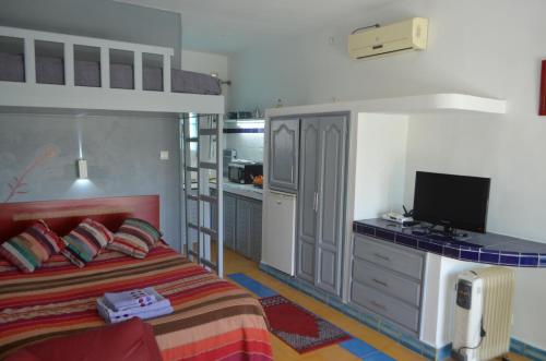a bedroom with a bed and a desk with a television at Studio Tishka in Oualidia