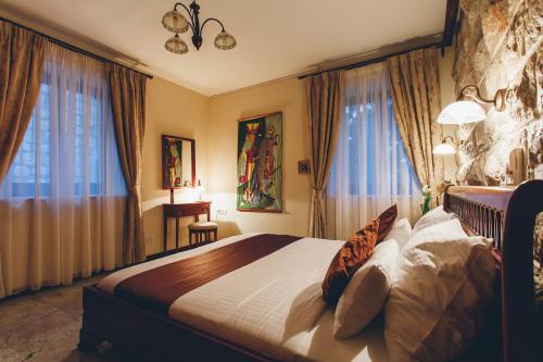 a bedroom with a large bed in a room with windows at Eco Hotel Carrubba in Tivat