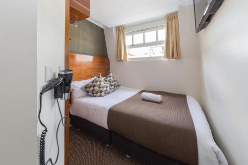 ロンドンにあるチェスター ホテルの小さなベッドルーム(ベッド1台、テレビ付)